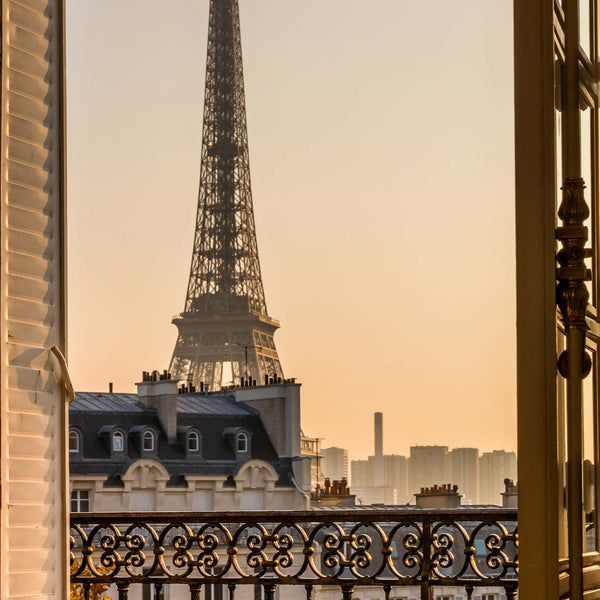 Paris balcony view with the Eiffel Tower glowing against a warm evening sky