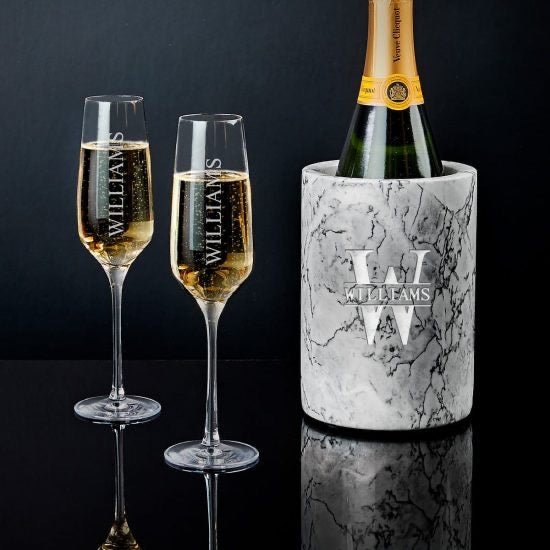 Two champagne flutes and a bottle of champagne in a marble cooler