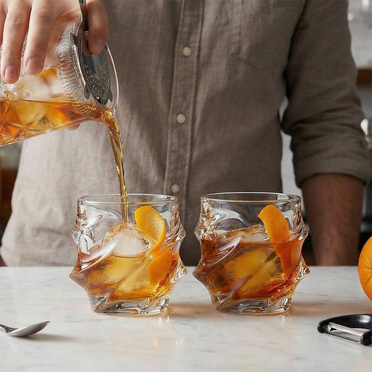 a man pouring cocktail on 2 sculpted glasses