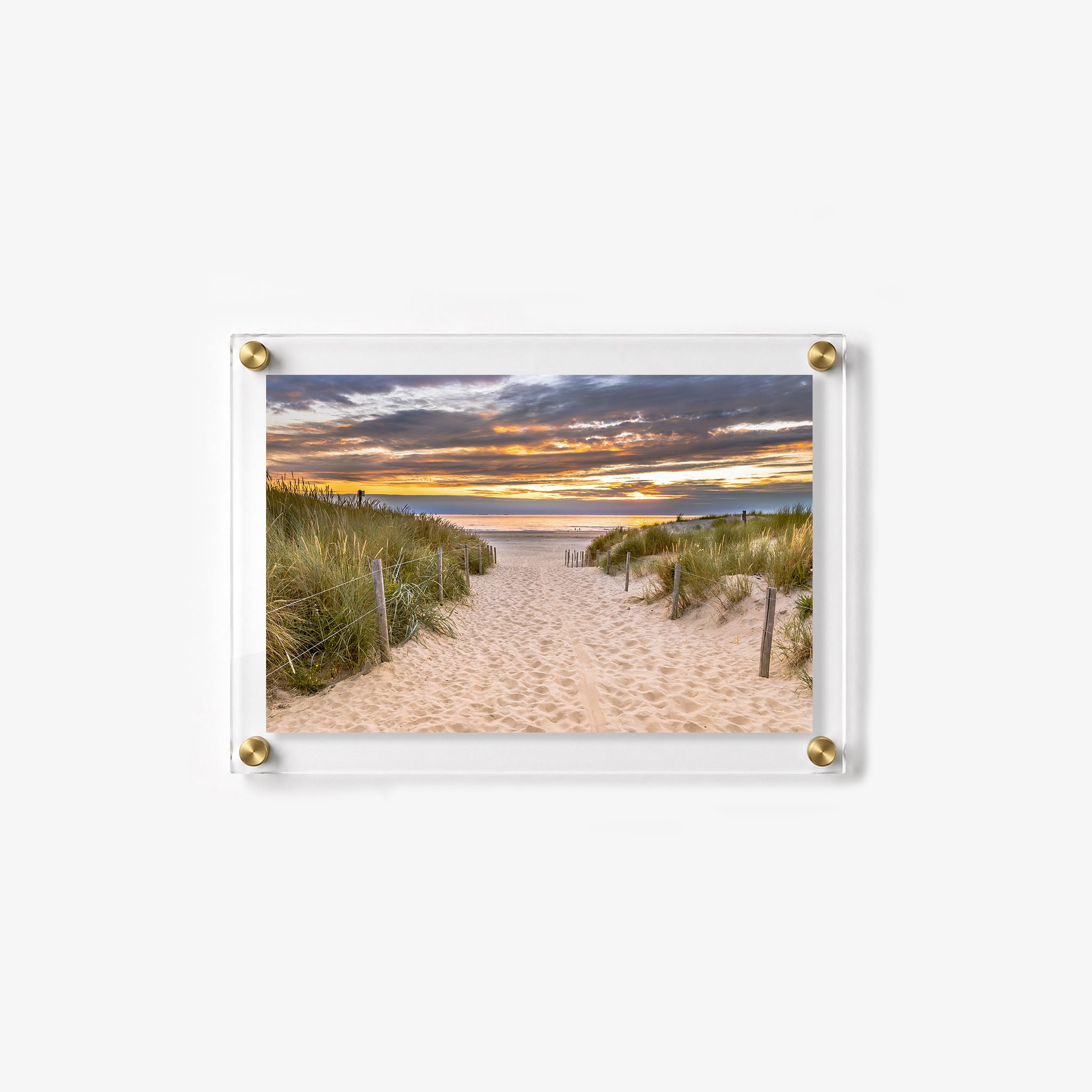 Scenic dune path leading to the sea as warm sunlight glows beneath layered clouds