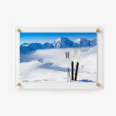 Scenic ski slope photograph with upright skis, chairlifts, and snow covered peaks