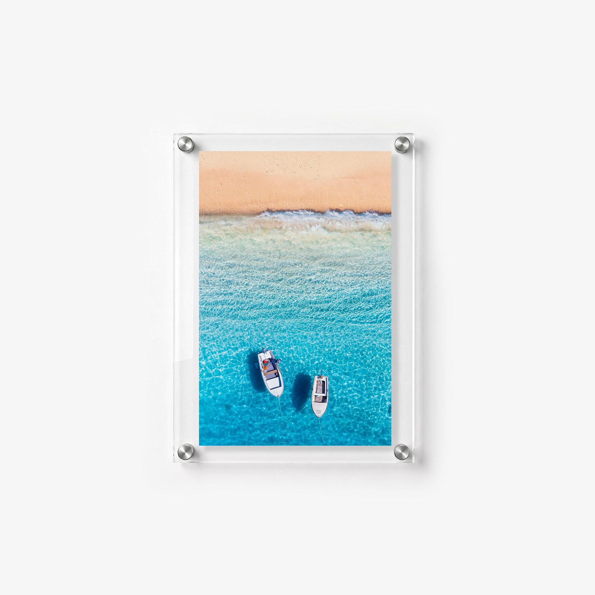 Two boats rest in shallow blue water as waves roll toward the shore