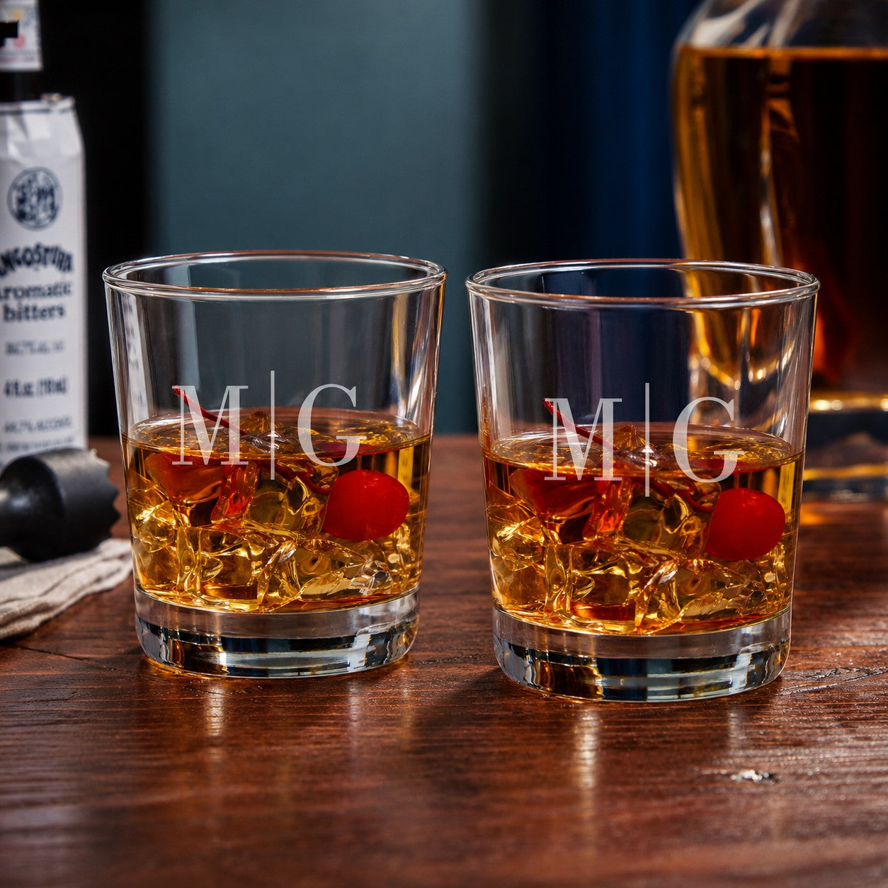 Two glasses of whiskey with cherries and initials 'M' and 'G' on a wooden surface.