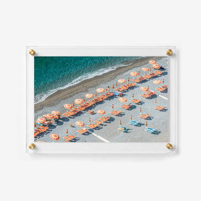 Overhead coastal photograph showing orange chairs arranged beside a calm blue shoreline