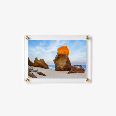 Large weathered rock formation standing on a quiet beach 