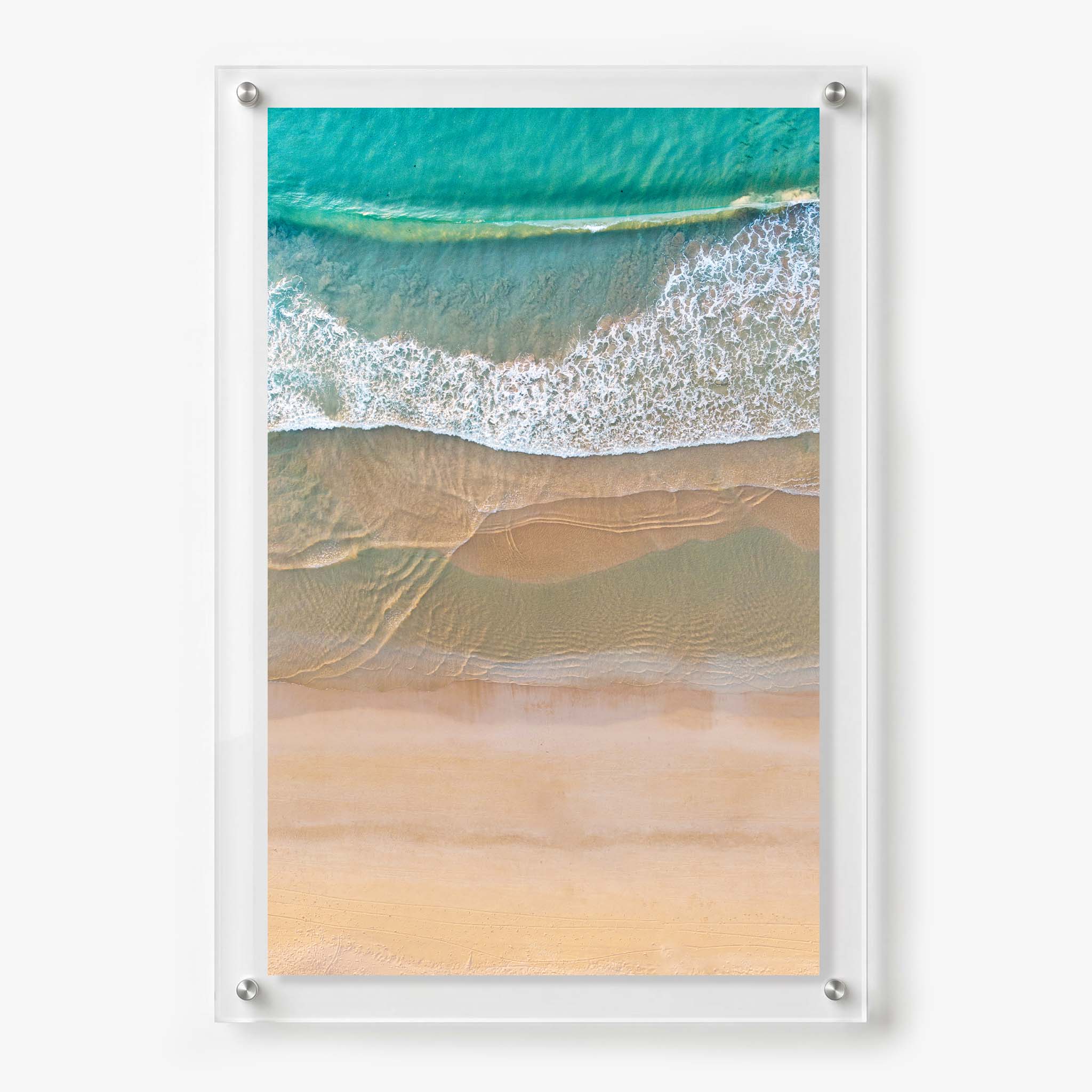 Acrylic wall art featuring an aerial view of turquoise waves washing onto a soft sandy beach