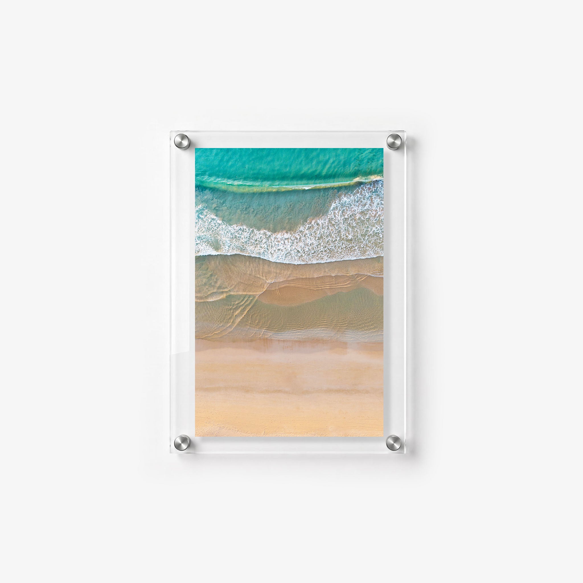 Aerial beach scene with turquoise water, foamy waves, and layered bands of wet sand