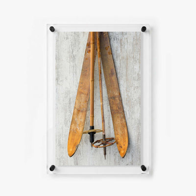Vertical acrylic wall art print featuring worn wooden skis and vintage winter sports equipment