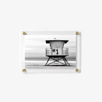 Monochrome acrylic print of a lifeguard hut centered against the sea and cloudy sky
