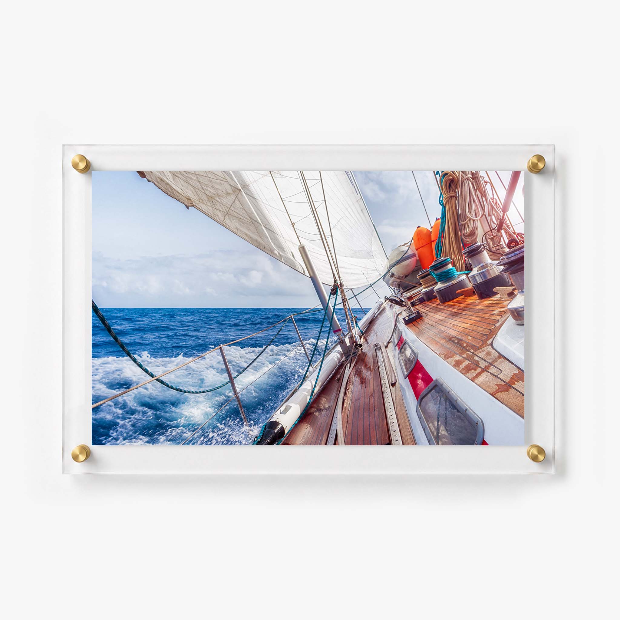 Sailboat deck with polished wood, coiled ropes, white sails, and foaming ocean water